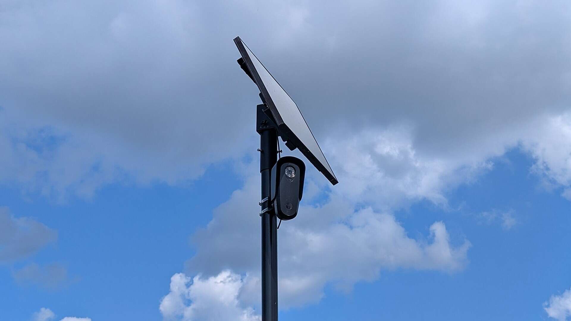 Flock Safety license plate reader camera with a solar panel on a black pole