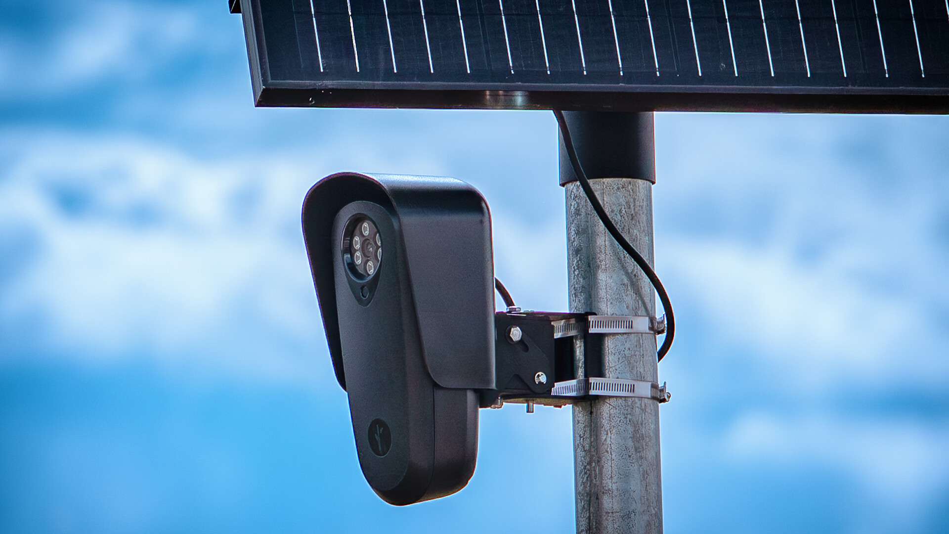 A pole-mounted Flock Safety license plate reader camera beside a road