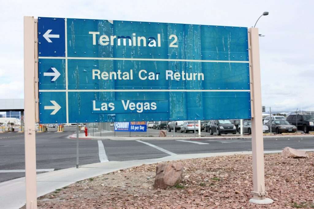 Blue roadside sign at the Las Vegas airport pointing to Terminal 2, Rental Car Return and Las Vegas