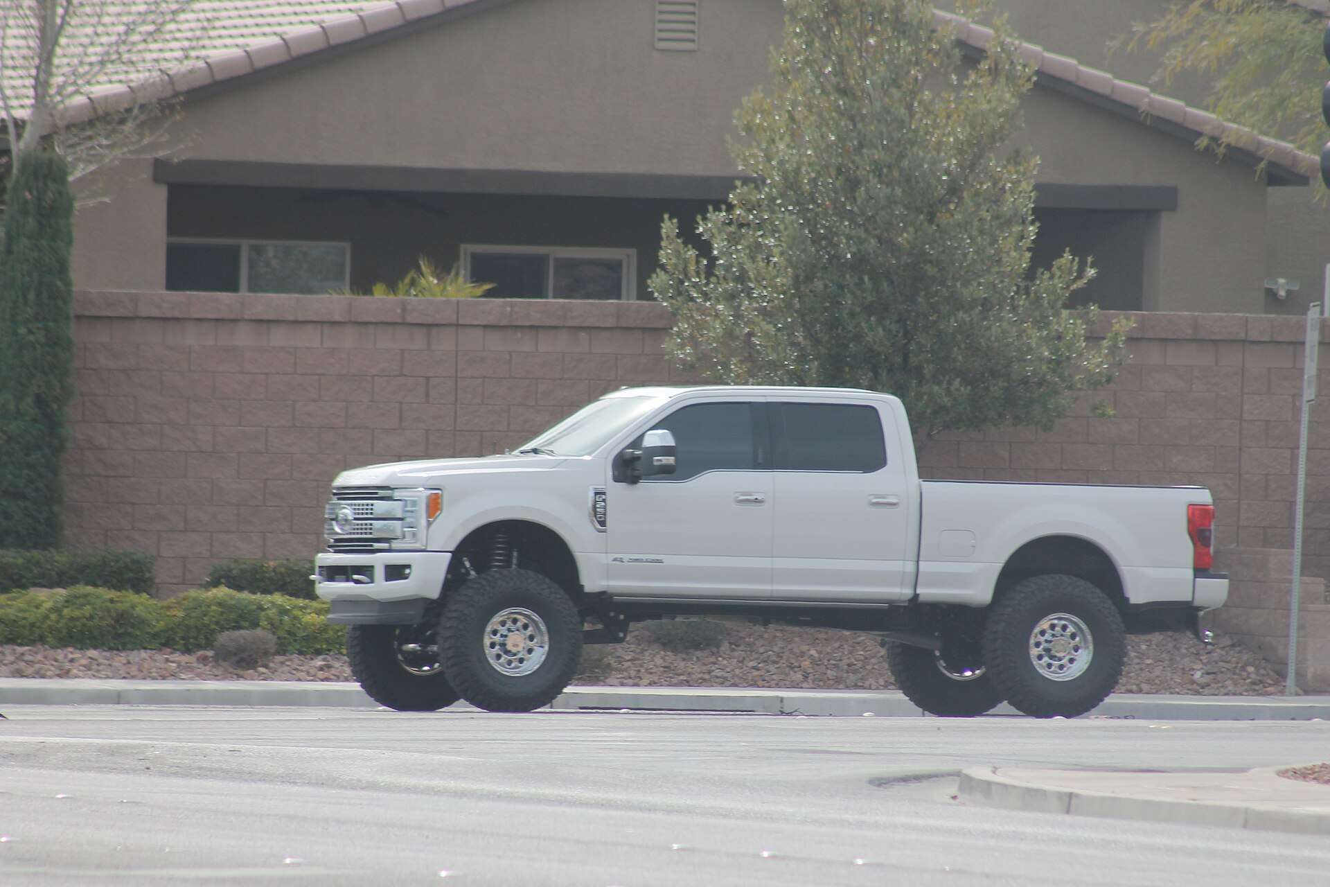 A lifted white Ford F-250 Super Duty pickup stopped at an intersection