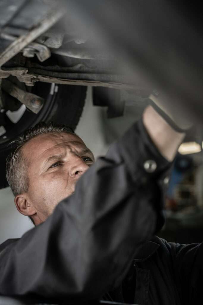 Mechanic reaching up to work on the underside of a car on a lift