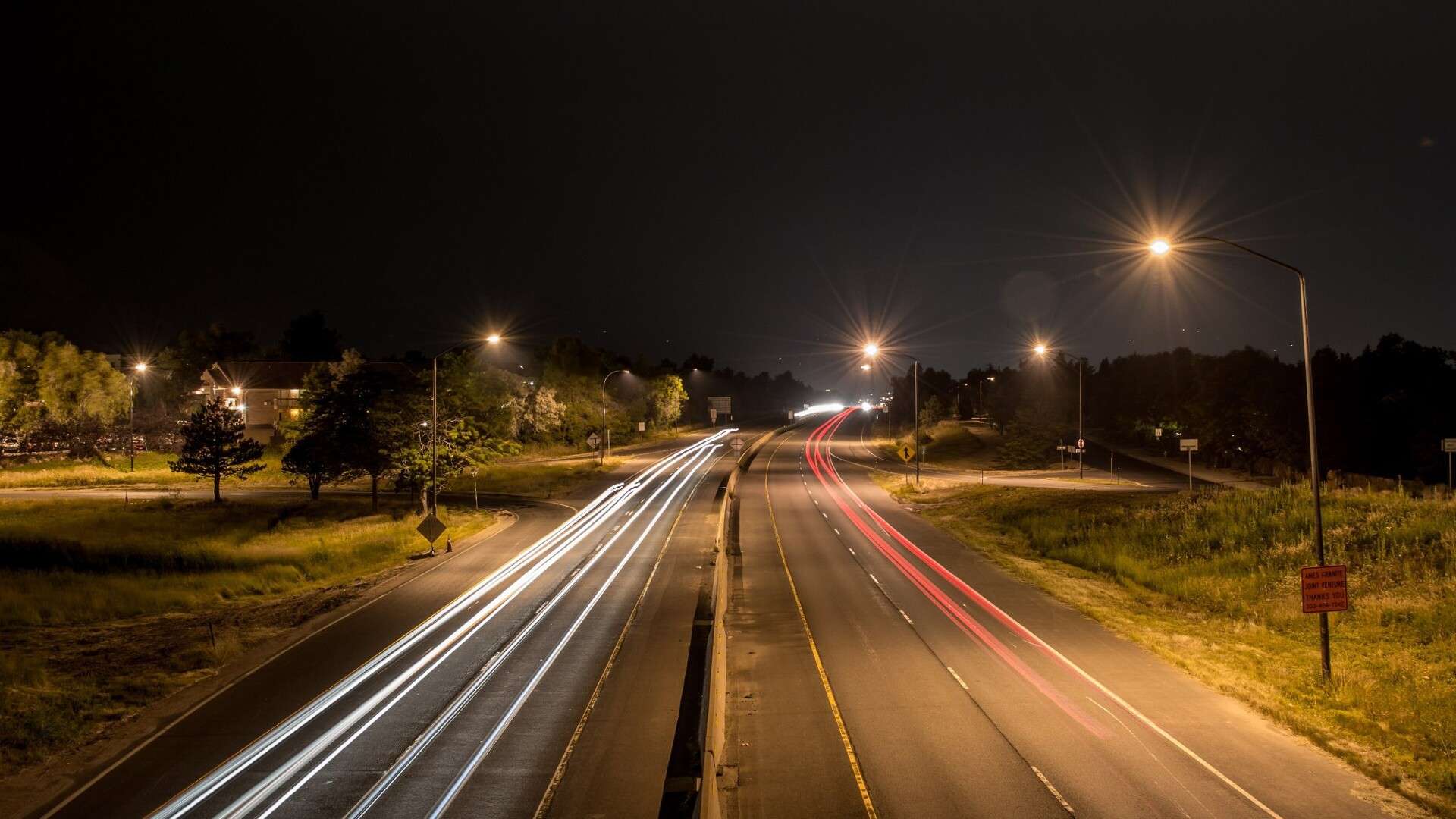 Long-exposure photo of headlight and taillight trails on a divided road at night