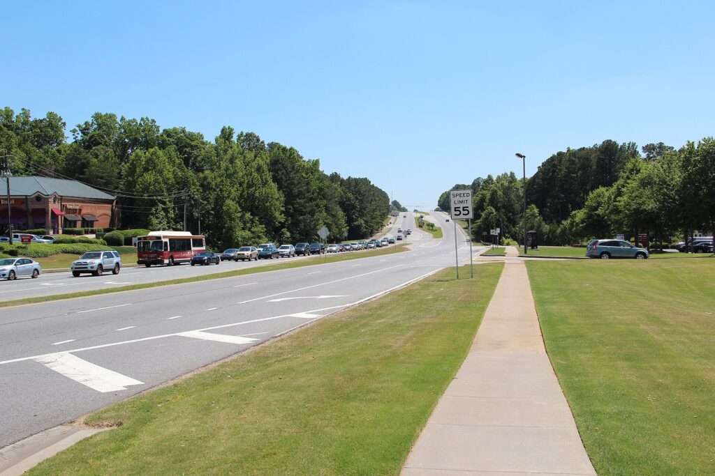 Divided multilane Peachtree Industrial Boulevard, Georgia State Route 141, with a grass median and sidewalk in Peachtree Corners