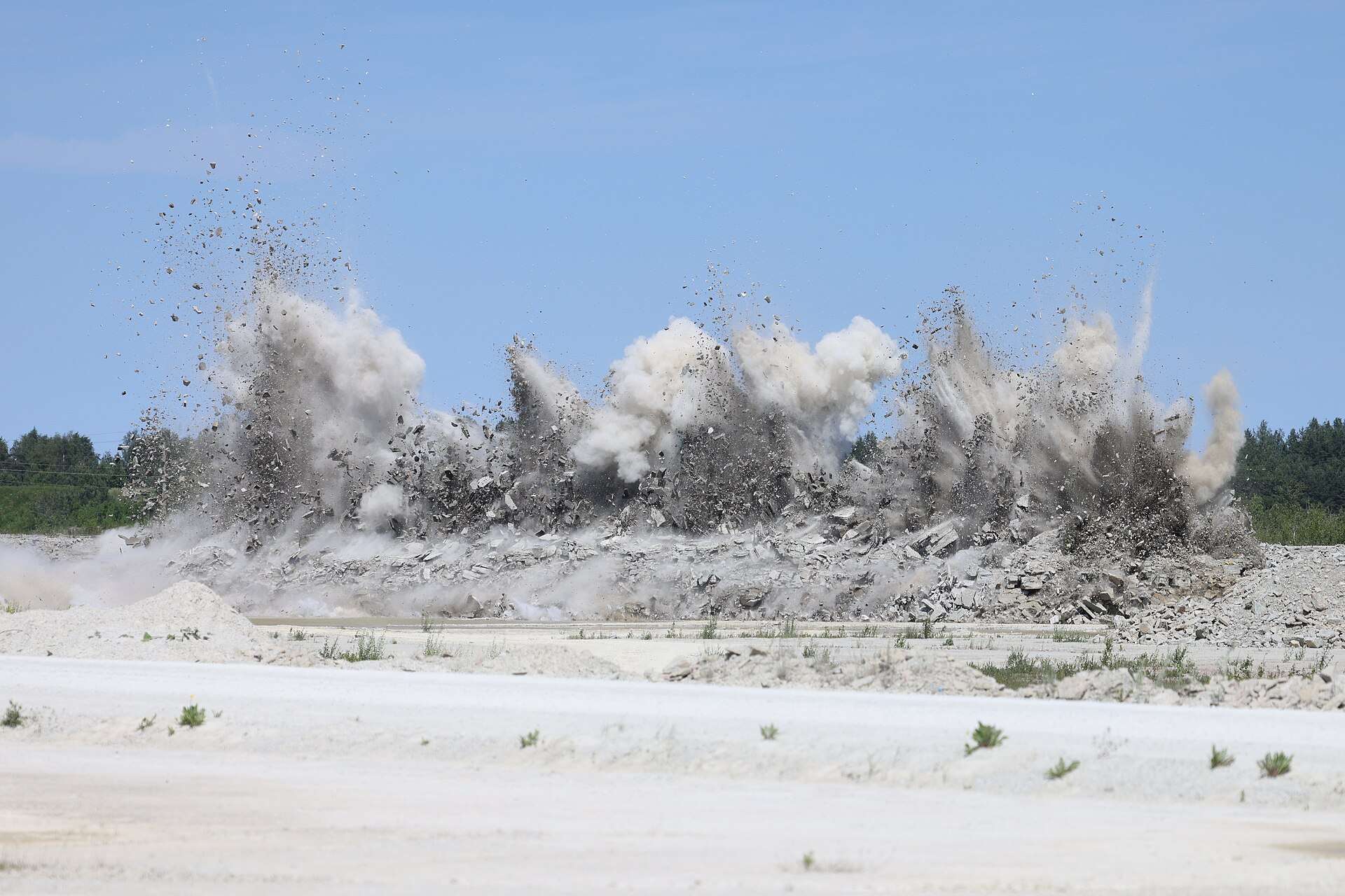 Rock blast throwing debris and dust at a limestone quarry