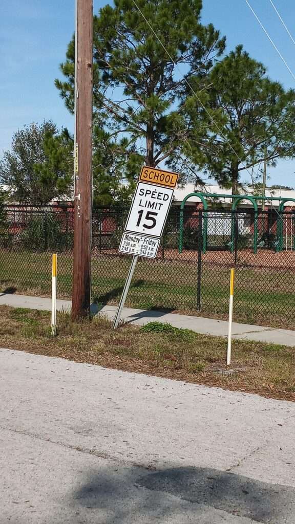 School zone sign posting a 15 mph speed limit beside a school fence in Largo, Florida
