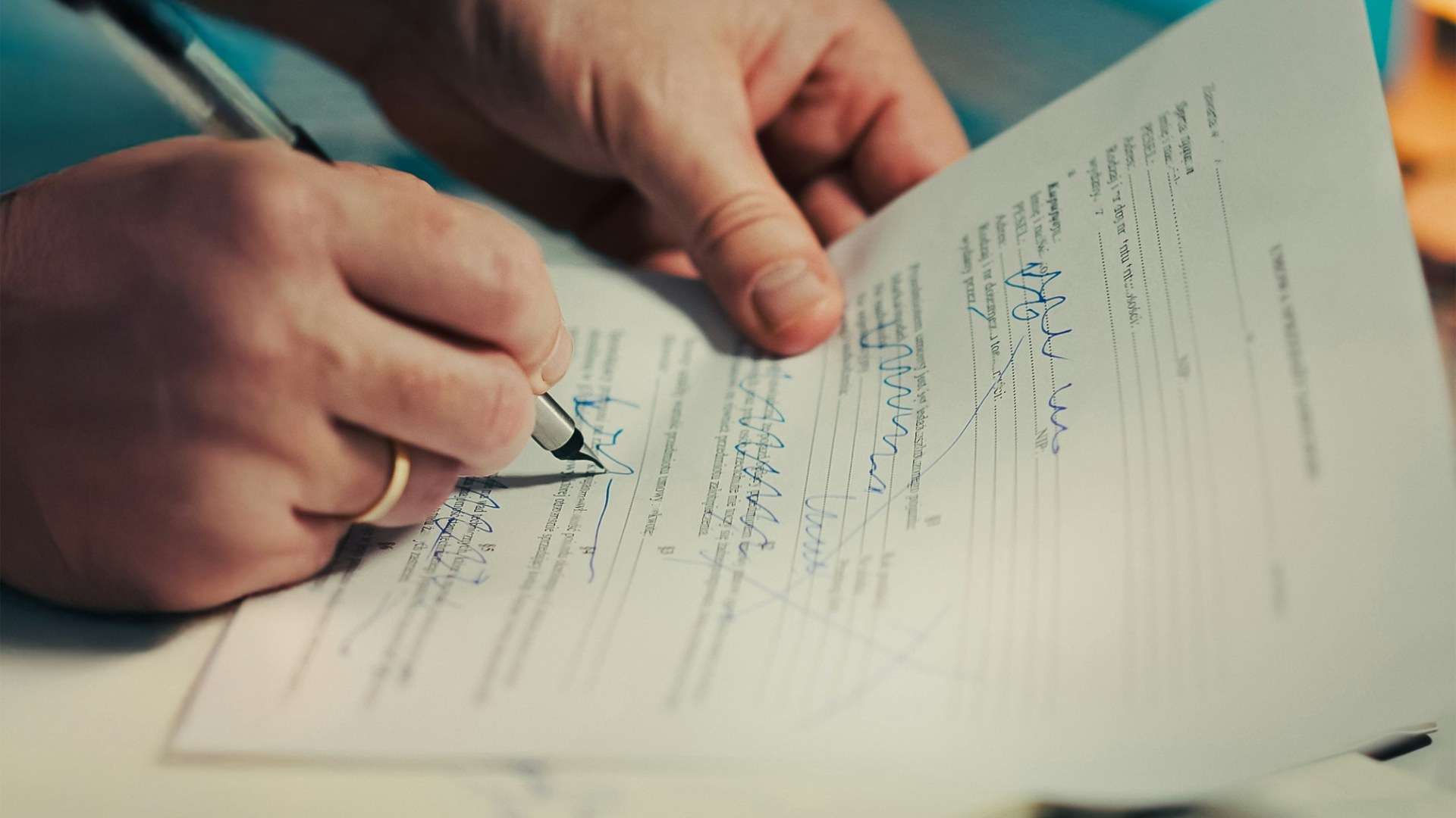 A buyer signs a purchase document with a pen