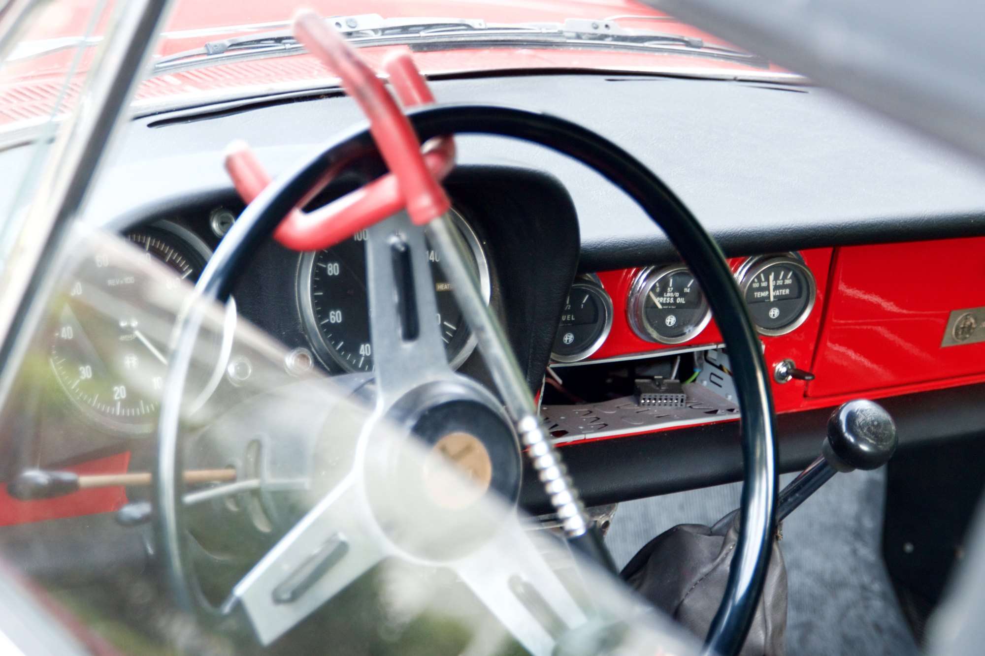 Red steering-wheel lock clamped across a car steering wheel