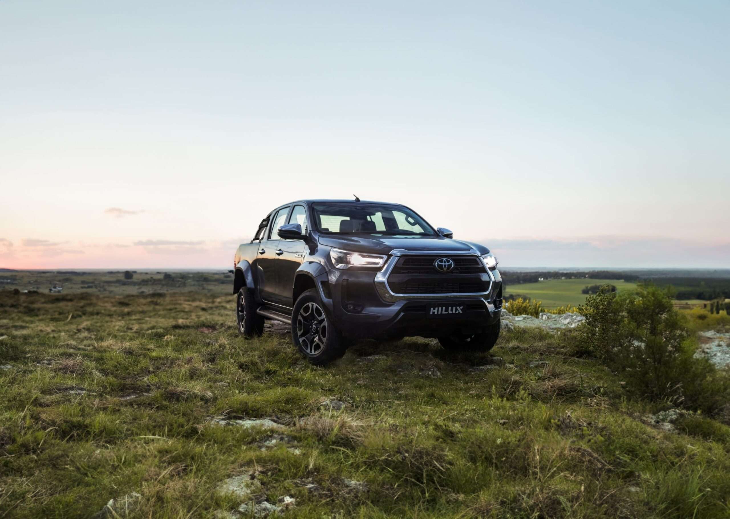 Current-generation Toyota Hilux built in Zárate, Argentina, parked on a grassy hillside at dusk