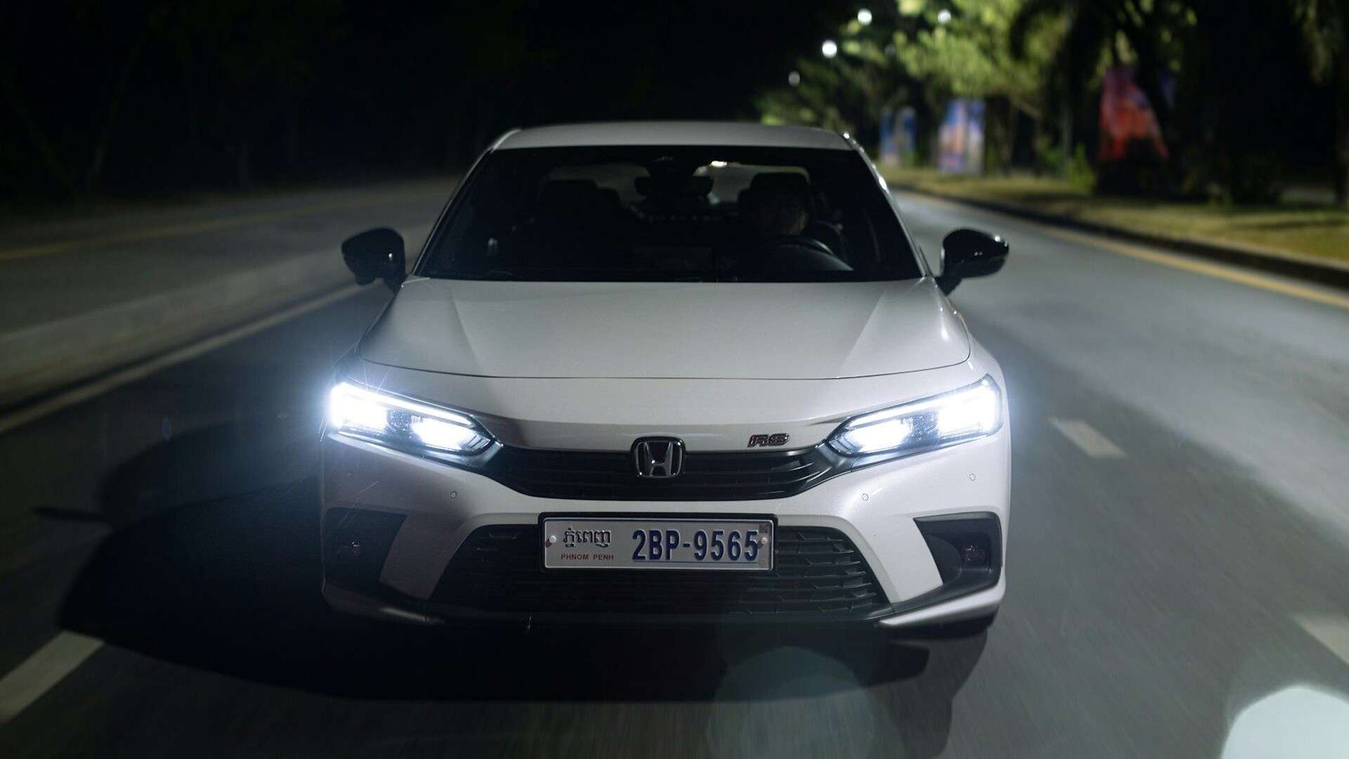 a white car driving down a street at night