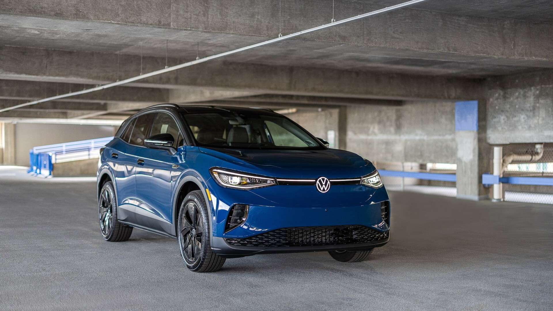 A blue 2025 Volkswagen ID.4 parked on a level of a concrete parking garage